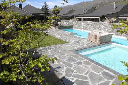 an image of a swimming pool in a yard with a stone wall at Cardrona Ski Apartment in Wanaka
