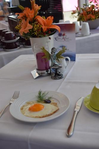 a plate with an egg on a table with a vase of flowers at Eden Hotel in Bad Krozingen