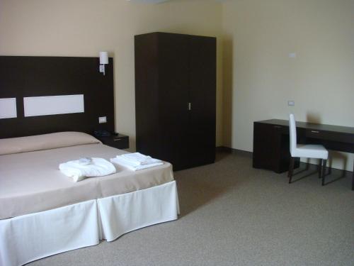 a bedroom with a bed and a desk and a chair at Santa Loja Hotel Residence in Tito