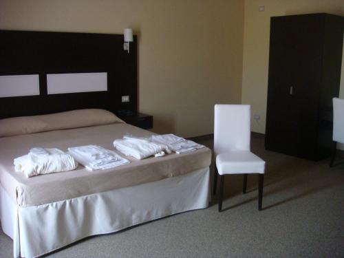 a bedroom with a bed and a white chair at Santa Loja Hotel Residence in Tito