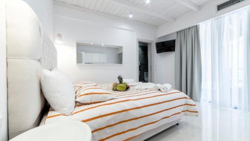 a white bedroom with a striped bed and a window at Liberte Maisonettes in Parga