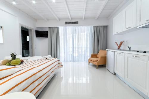 a white room with a bed and a kitchen at Liberte Maisonettes in Parga