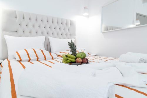 a white bed with a bowl of fruit on it at Liberte Maisonettes in Parga