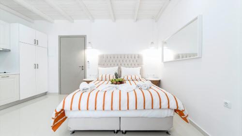 a white bedroom with a large bed with orange and white stripes at Liberte Maisonettes in Parga