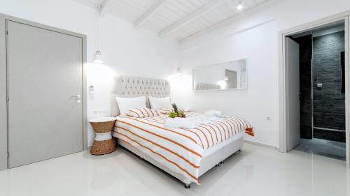 a white bedroom with a bed with a striped blanket at Liberte Maisonettes in Parga