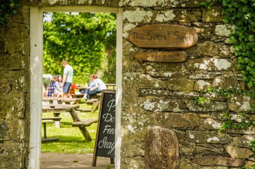 a brick wall with a sign on it with people sitting at tables at The Grove in St. Davids