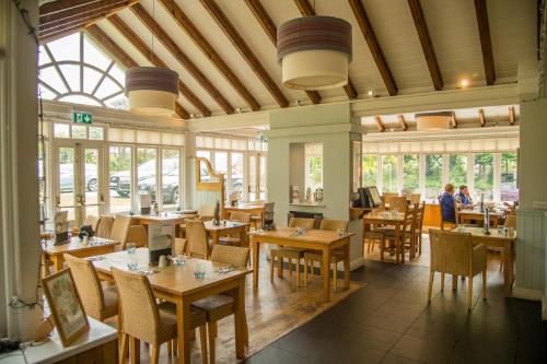a restaurant with wooden tables and chairs and windows at The Grove in St. Davids