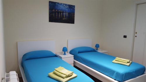 two beds in a room with blue sheets at CasaLù in Palermo