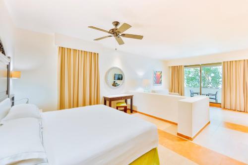a white bedroom with a bed and a ceiling fan at Occidental at Xcaret Destination - All Inclusive in Playa del Carmen