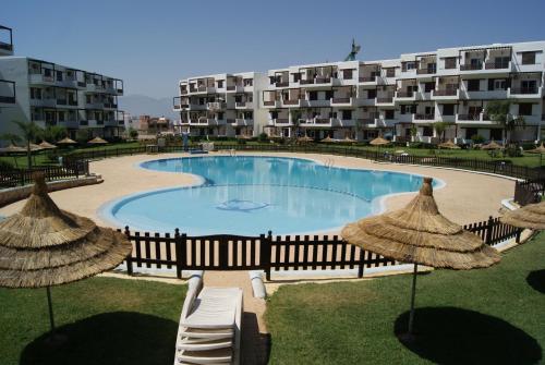 a swimming pool with chairs and umbrellas in front of a building at Appartement Miradorgolf in Cabo Negro