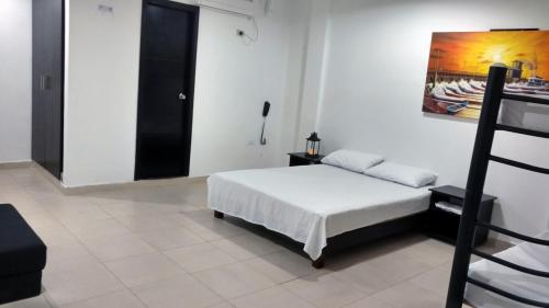 a bedroom with a bed and a painting on the wall at Hotel El Emigrante in Puerto Colombia
