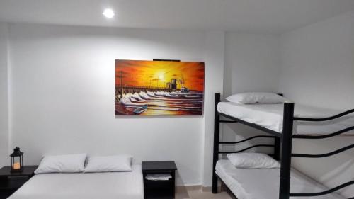 a room with two bunk beds and a painting on the wall at Hotel El Emigrante in Puerto Colombia