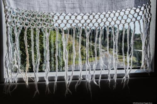 a window with a white curtain with a view at Bio Agriturismo Poggio Aione in Saturnia