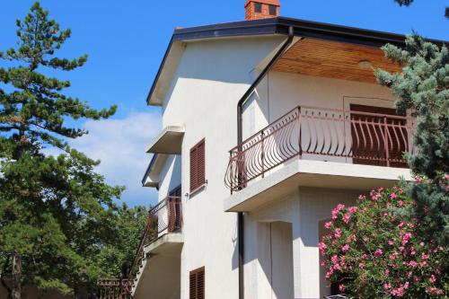 a white building with a balcony and pink flowers at Apartmani Mia in Jadranovo
