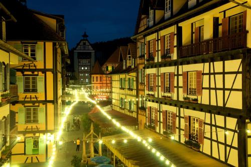 a city street with buildings and lights at night at Colmar Tropicale in Bukit Tinggi