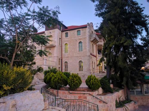 a large stone house with a fence in front of it at Alhambra Palace Hotel Suites - Ramallah in Ramallah