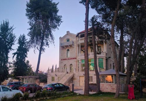 an old house with cars parked in front of it at Alhambra Palace Hotel Suites - Ramallah in Ramallah