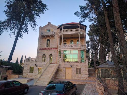 a large stone house with two cars parked in front of it at Alhambra Palace Hotel Suites - Ramallah in Ramallah