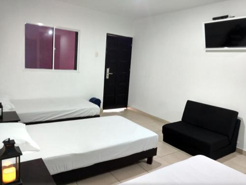 a hotel room with two beds and a chair at Hotel El Emigrante in Puerto Colombia