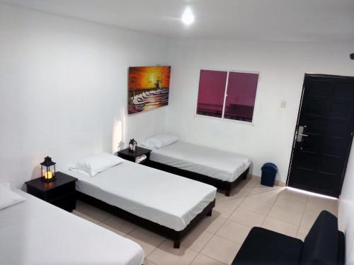 a room with two beds and a table with a lamp at Hotel El Emigrante in Puerto Colombia