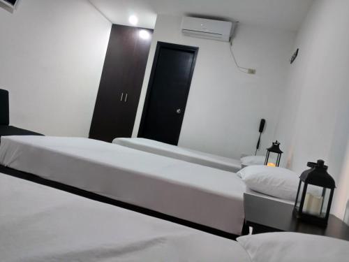 a bedroom with two beds and a mirror at Hotel El Emigrante in Puerto Colombia