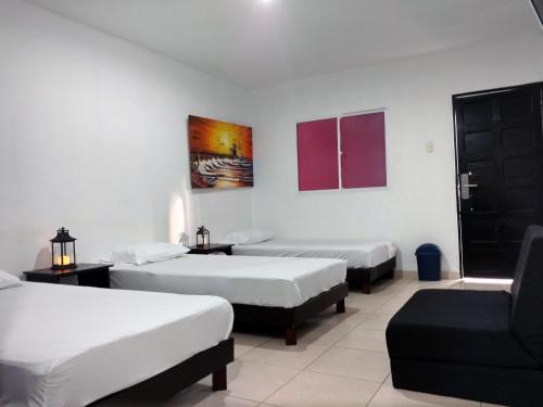 a hotel room with two beds and a couch at Hotel El Emigrante in Puerto Colombia