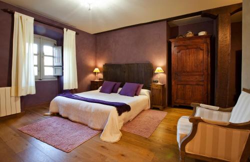 a bedroom with a large bed with purple pillows at Casa Rural Zigako Etxezuria in Ziga