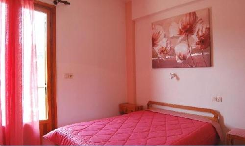 a bedroom with a bed with a pink bedspread and a window at Anais Studios in Patitiri