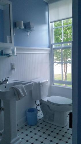 a bathroom with a toilet and a sink and a window at Wades Point Inn on the Bay in Saint Michaels