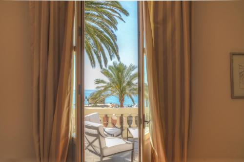 a room with a view of the beach and palm trees at Hotel De La Plage in Pietra Ligure