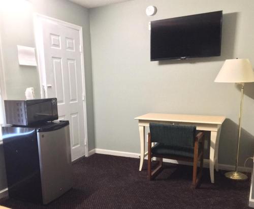 Cette chambre d'hôtel dispose d'une table et d'une télévision murale. dans l'établissement Overton Motel, à Livingston
