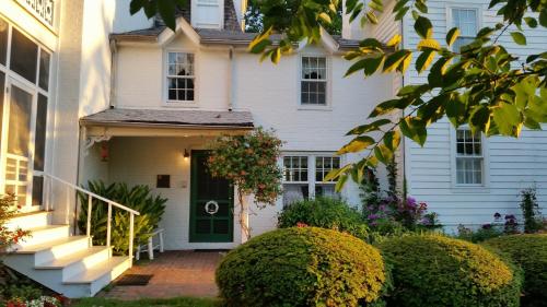 a white house with a green door and bushes at Wades Point Inn on the Bay in Saint Michaels