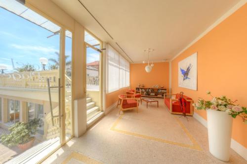 a living room with orange walls and large windows at Hotel De La Plage in Pietra Ligure
