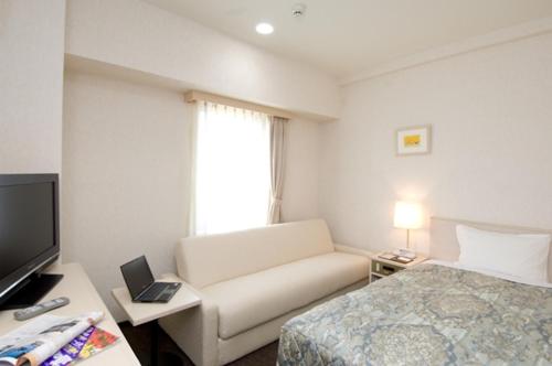 a hotel room with a couch and a bed and a television at Hotel Unisite Mutsu in Mutsu