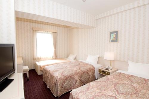 a hotel room with two beds and a flat screen tv at Hotel Unisite Mutsu in Mutsu