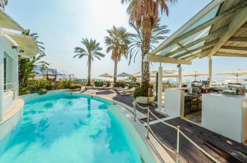 a swimming pool with a view of the beach and palm trees at Hotel De La Plage in Pietra Ligure