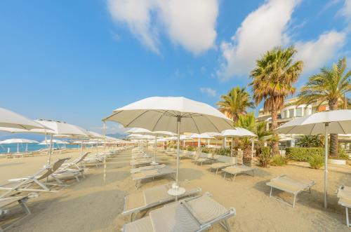 a row of chairs and umbrellas on a beach at Hotel De La Plage in Pietra Ligure