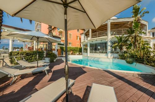 a patio with chairs and umbrellas next to a pool at Hotel De La Plage in Pietra Ligure