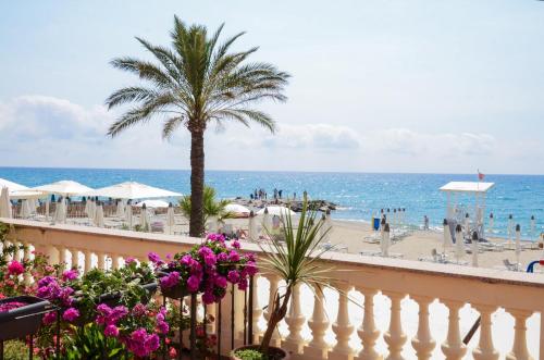 a balcony with a palm tree and the beach at Hotel De La Plage in Pietra Ligure