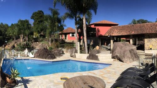 una piscina en un complejo con sillas y un edificio en Pousada Sítio da Luzia, en Engenheiro Passos