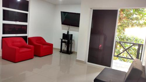 sala de estar con 2 sillas rojas y TV de pantalla plana en Hotel El Emigrante, en Puerto Colombia