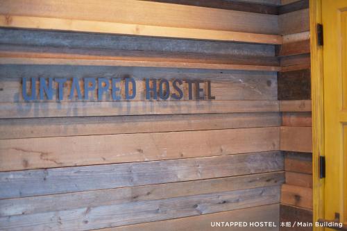 a sign on a wood wall with the words un attempted hospital at Untapped Hostel in Sapporo