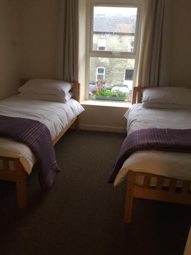2 camas individuales en una habitación con ventana en O'Loughlin's Bar, en Miltown Malbay