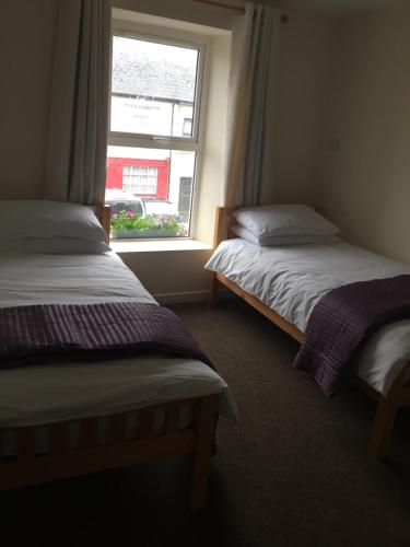 two beds in a room with a window at O'Loughlin's Bar in Miltown Malbay