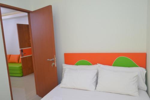 a bedroom with a bed with an orange headboard and white pillows at Titanium Express HomTel in Jakarta