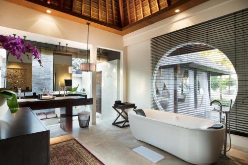 a bathroom with a tub and a sink and a desk at The Royal Santrian in Nusa Dua