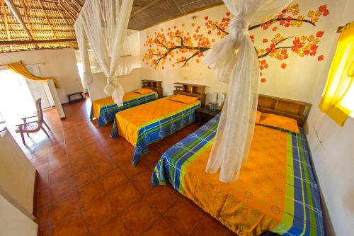 a room with three beds in a room at Hotel Cafe del Sol in Monterrico