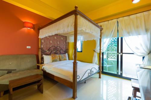 a bedroom with a canopy bed and a chair at 花蓮觀月民宿-近車站-寵物友善-含車位可包棟8-14位 烤肉麻將僅提供給包棟使用 in Hualien City