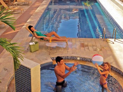 a man and woman playing in a swimming pool at Malibu Palace Hotel in Cabo Frio