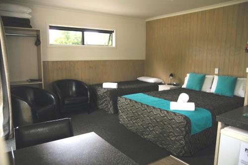 a hotel room with a bed and a chair at Geraldine TOP 10 Holiday Park in Geraldine